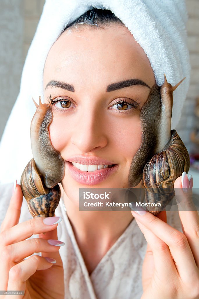 portrait of  woman with snails on her face portrait of smiling young darkhaired woman with snails achatina giant on her face Dermatology Stock Photo