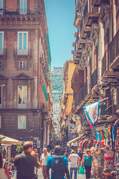 Naples, Italy - July 28, 2015: Narrow street in the center of Naples, with its traditional architecture, cafes and shops. Locals and tourists are walking through. 