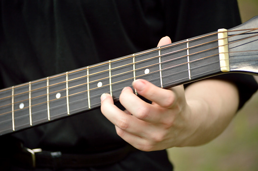 Guitarist playing E chord on the fretboard of the guitar.