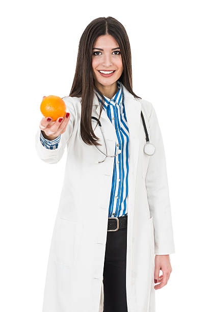 giovane medico femmina attraente indossando uniformi e con frutta - orange uniform foto e immagini stock