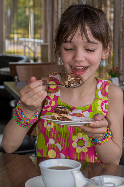 Little girl in a cafe eating chocolate cake with cream