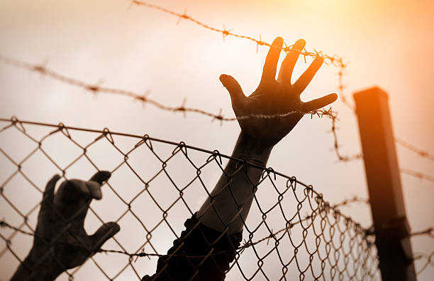 беженцев мужчин и ограждение. концепция беженцев - barbed wire фотографии стоковые фото и изображения