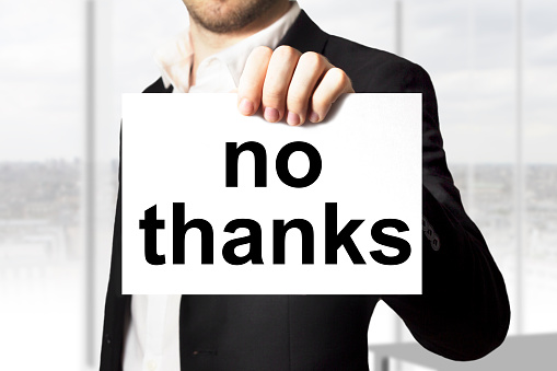 businessman in black suit holding sign no thanks