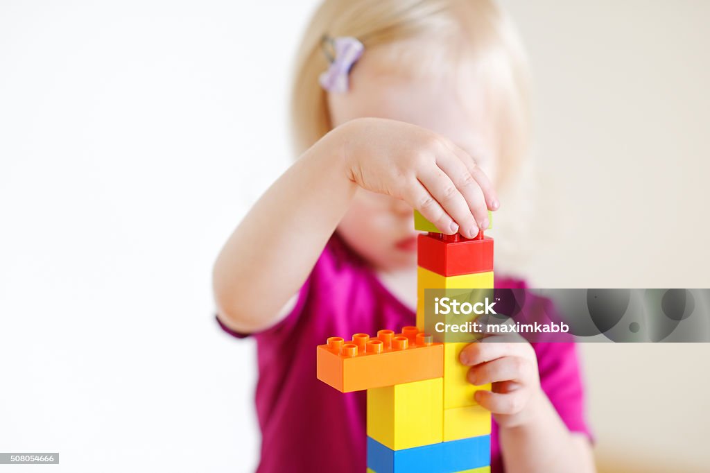Cute toddler girl playing with colorful blocks Cute little toddler girl playing with colorful plastic blocks at home 12-17 Months Stock Photo