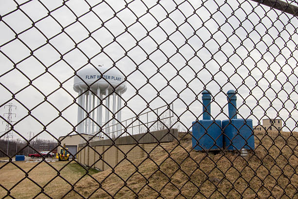 Flint Michigan Water Tower Through Chain Link Fence Flint, Michigan, USA - February 2, 2016: The exterior of the Flint Water Plant in Michigan. Flint is in the spotlight as concerns over it's water quality and lead content have made national headlines. flint michigan stock pictures, royalty-free photos & images