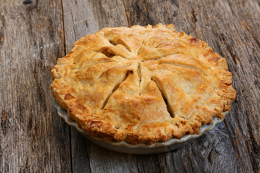 Delicious whole fresh baked rustic Apple Pie with table setting 