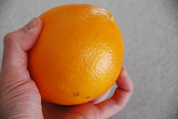 istock Hand Holding Unpeeled Orange 508066090