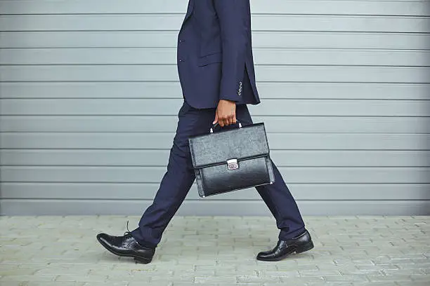 Legs of businessman in suit walking to work in the morning