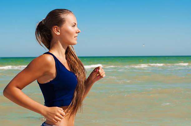 Young beautiful girl athlete playing sports on the beach stock photo