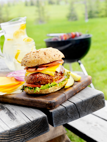 A Back Bacon or Grilled Ham Cheeseburger with Lettuce,Tomato and Pickles at an Outdoor BBQ-Photographed on Hasselblad H3D2-39mb Camera