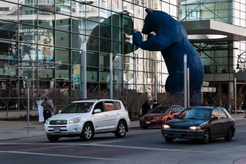 Denver, USA - February 16, 2014: A variety of people on the street and a bear peaking inside the Colorado Convention Center in downtown Denver. It's a venue for conventions, exhibits, and other event.