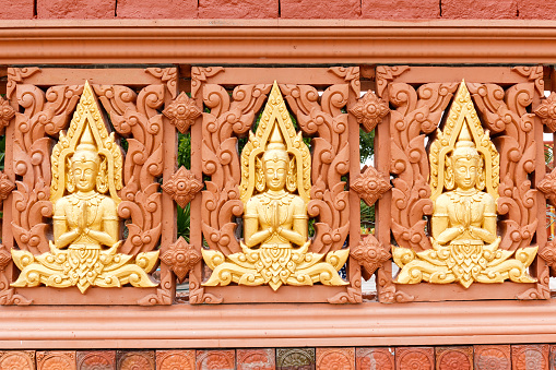 Row of Buddha statues in Buddhist temple wall, Generally in Thailand, any kinds of art decorated in Buddhist church, temple , chapel, pavilion, temple hall, monk’s  house etc. created with money donated by people to hire artist. They are public domain or treasure of Buddhism, no restrict in copy or use, no name of artist appear (but, if there is artist name, it only for tell who is the artist of work, not for copyright). This photo is taken under these conditions.