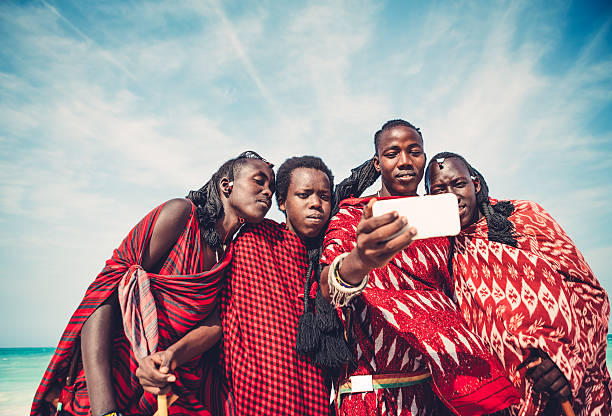 Masai Taking A Selfie Group of Masai warriors in traditional clothing taking a selfie with smart phone (Zanzibar, Africa). masai stock pictures, royalty-free photos & images