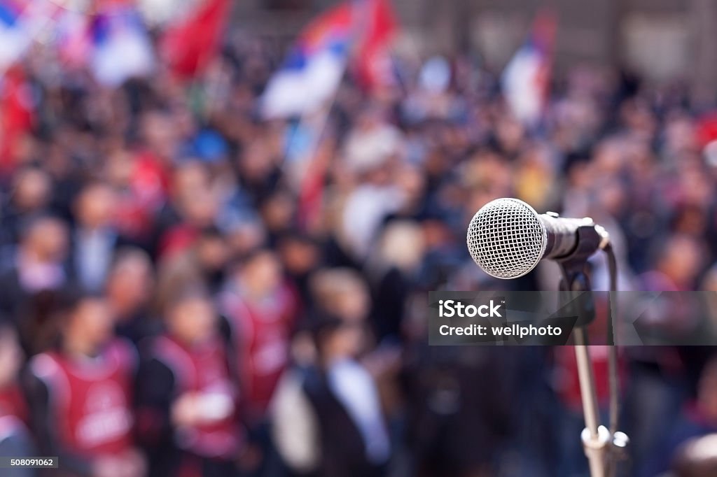 Protest. Public demonstration. Microphone in focus against unrecognizable crowd Political Rally Stock Photo