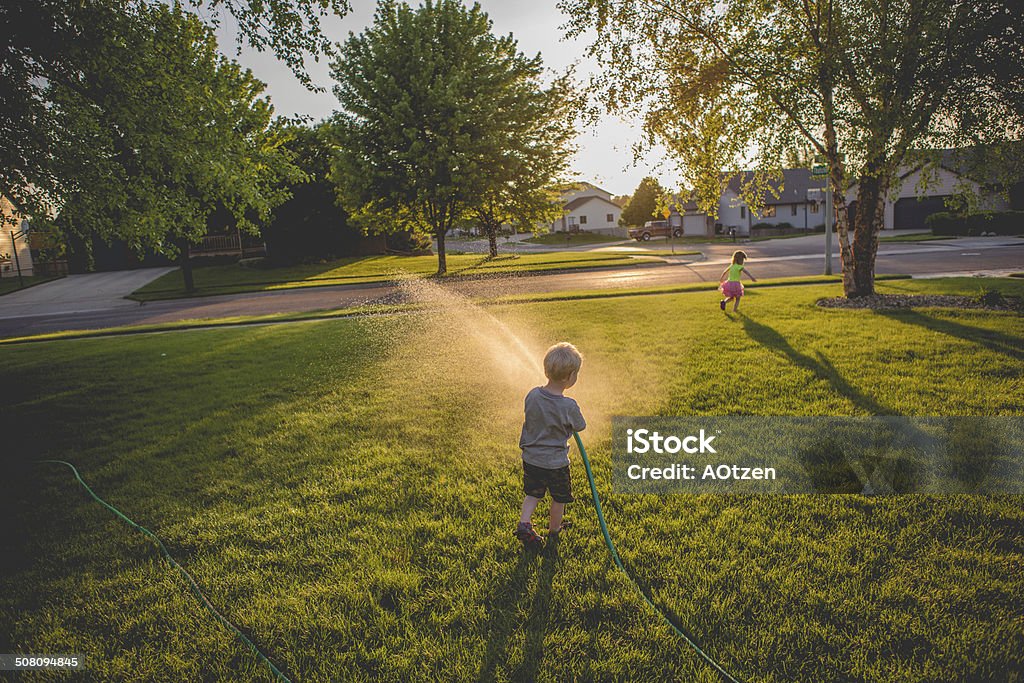 Playing with the garden hose Little boy chases his sister with a garden hose. Garden Hose Stock Photo