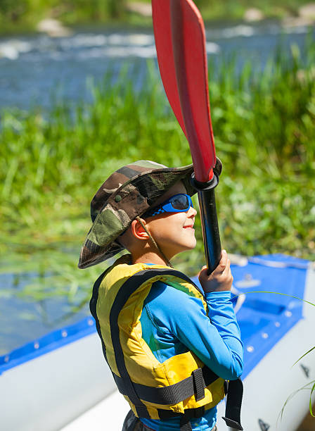 heureux jeune garçon tenant un kayak pagaie à proximité - foal child mare horse photos et images de collection