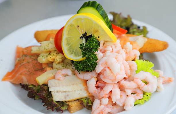 Stjerneskud - a Danish open sandwich Stjerneskud - English "Star" - is a traditional Danish cuisine open sandwich with schrimps, salmon, fillet of plaice, lemon, tomato, cucumber, parsley and asparagus on a piece of bread. danish culture stock pictures, royalty-free photos & images