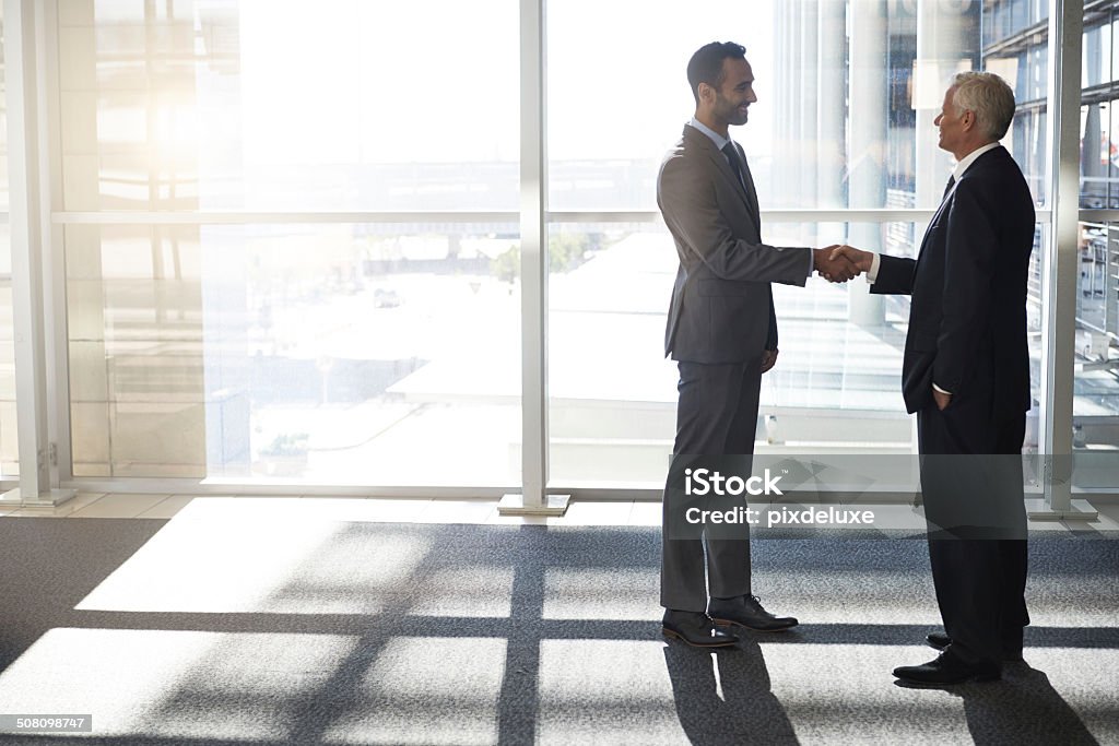 Welcome to our family Full length shot of a young and mature businessman shaking hands Business Stock Photo
