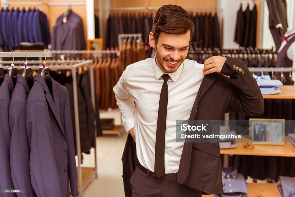 People in suit shop Modern young handsome businessman smiling and trying on classical suit in the suit shop Shopping Stock Photo