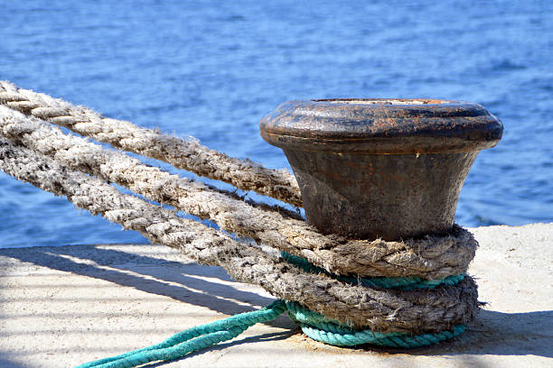 Thick boat ropes tied to an old rusty bollard stock photo