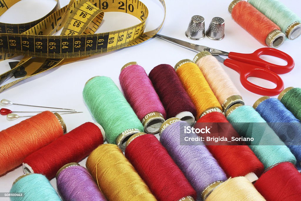 Sewing Stuff Colourful spools of thread, pins, thimbles, scissors and measure tape on white. Art And Craft Stock Photo