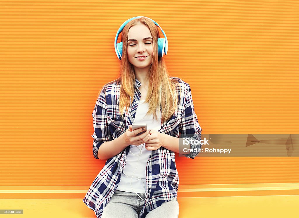 Girl listens and enjoys good music in headphones over colorful Happy girl listens and enjoys good music in headphones over colorful orange background Headphones Stock Photo