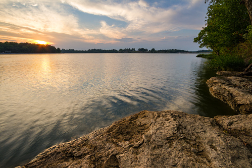 Vast view of the sunset from a rocky shoreline of Lake Jacomo located outside of the Kansas City Area