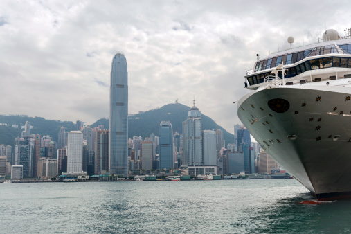 Hong Kong, China - May 3rd, 2014: Superstar Virgo Cruise Ship at the Ocean Terminal on the Kowloon Peninsula, beautiful skyline of the HK Island with 2IFC in the backgrounds.