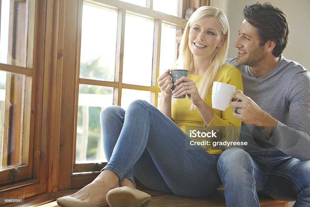 Love you more than that first sip of coffee Shot of a happy couple enjoying a hot drink together next to a window at home 30-39 Years Stock Photo