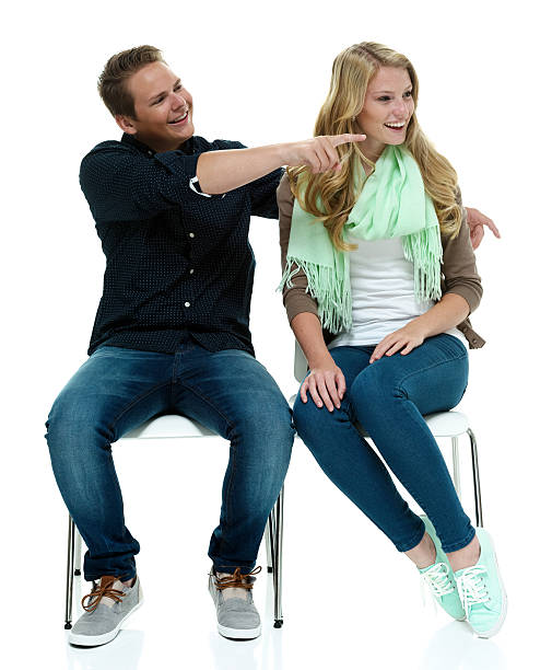 istock Cheerful couple sitting on chair & pointing away 508122559