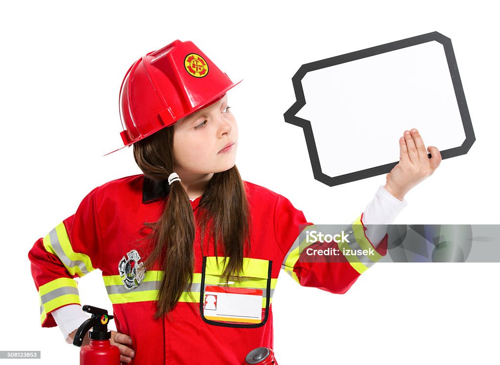 Young Female Firefighter Portrait of little girl dressed as a firefighter holding speech bubble in hand. Studio shot, isolated on white. Child Stock Photo