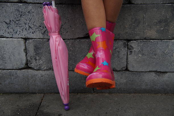 istock Child sitting legs in boots (Gumboots) holding a umbrella 508124921