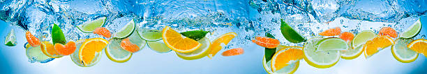 rodajas de frutas cítricas en azul agua - splashing orange fruit water fotografías e imágenes de stock