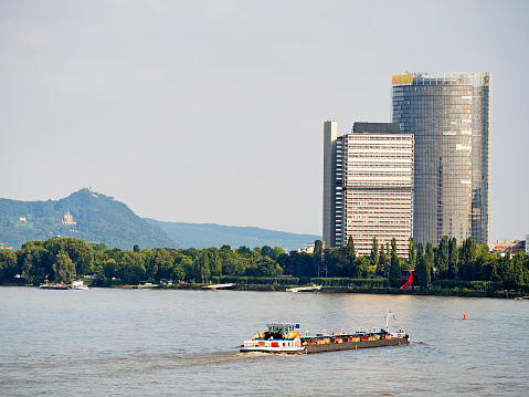 river Rhine with cargo ship and skyscraper in Bonn, Germany