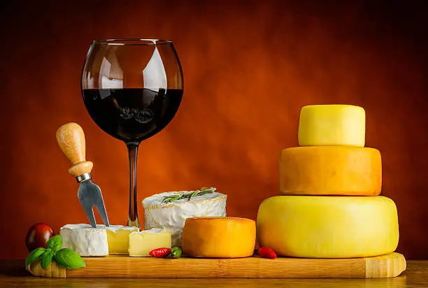 Glass of Red wine and cheese wheel with food and camembert