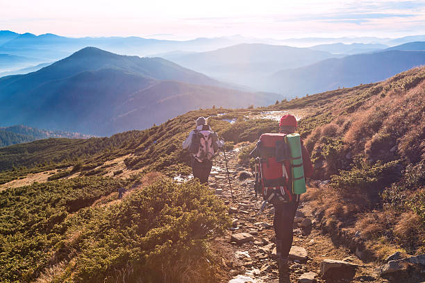 istock Two Hikers walking on Mountain Path Sunset Mountains Background 508135284
