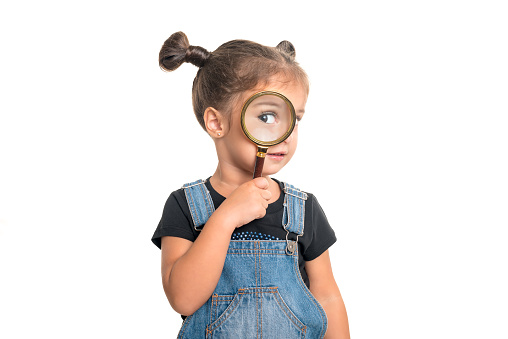 Cute baby girl  looking  through a magnifying glass.Isolated