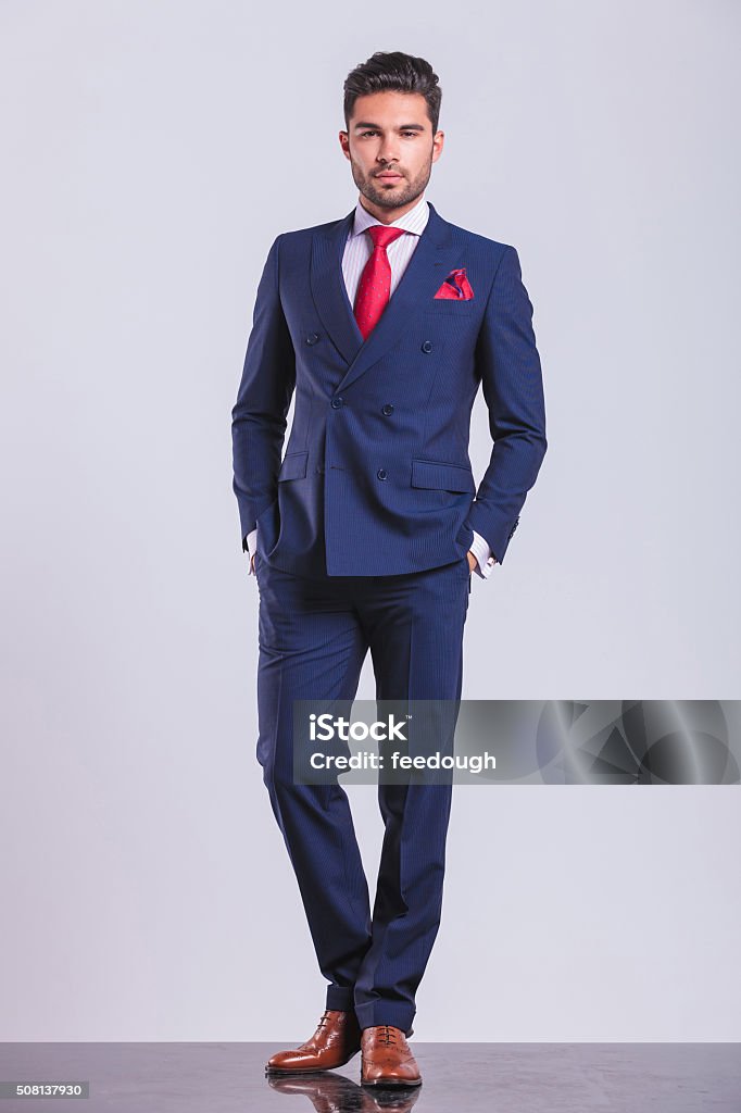 man posing on studio background with hands in pockets elegant man posing full body on studio background with hands in pockets Suit Stock Photo