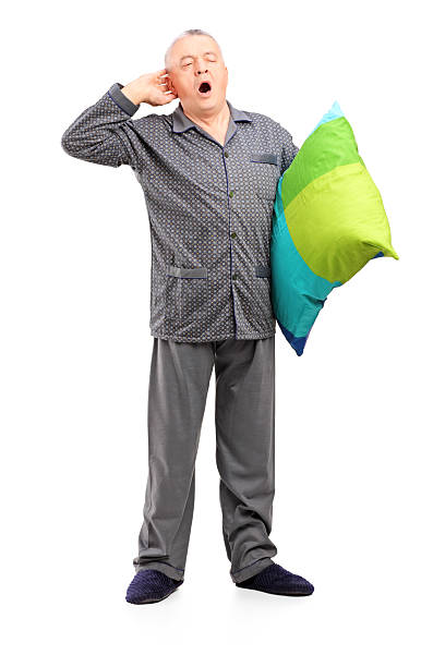 paisible homme d'âge mûr en pyjama tenant un oreiller - pillow wake up yawning sleeping photos et images de collection