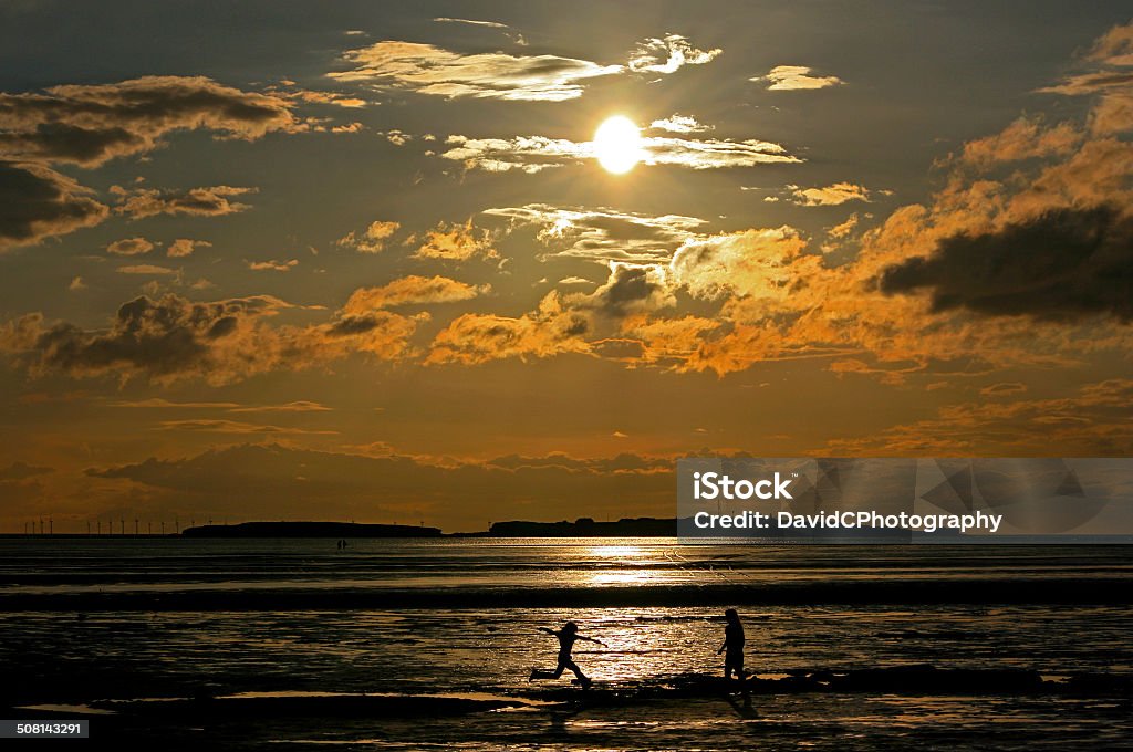 Hilbre Island Long Jump As the sun sets a golden scene is transformed by the foreground action of a silhouette leaping child.  Beach Stock Photo