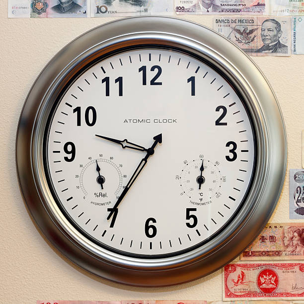 Time and Money A large round atomic clock with hygrometer and thermometer on a wall with parts of a variety of money. hygrometer photos stock pictures, royalty-free photos & images