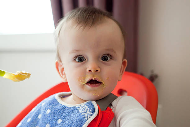 istock Surprised baby smeared with food, eats 508151136