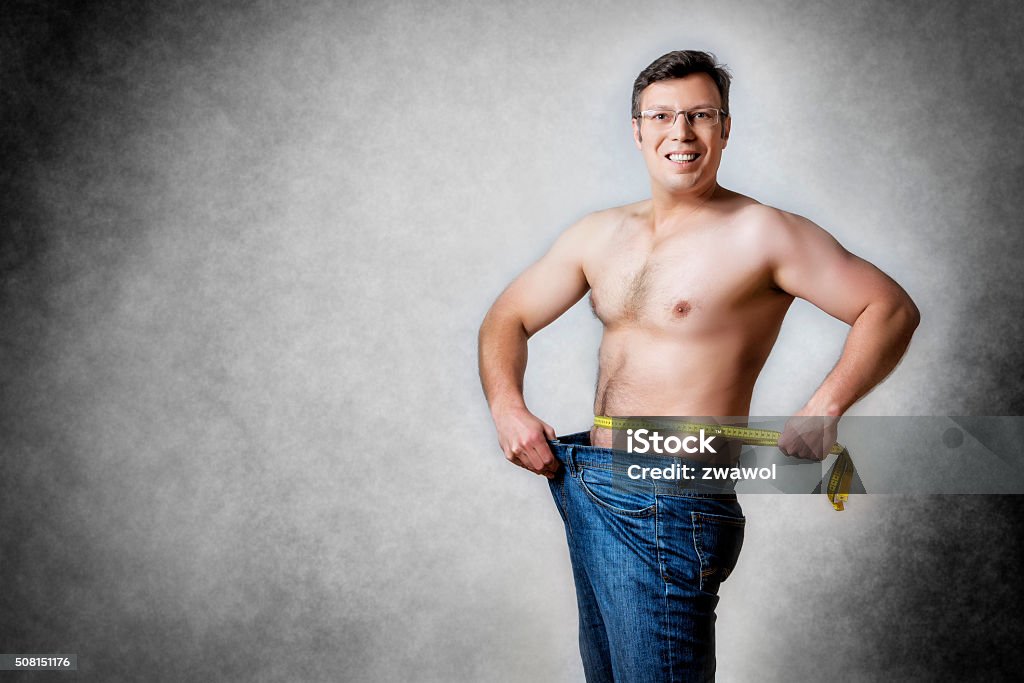 man with measuring tape Image of a man in blue jeans with measuring tape who has lost body weight Adult Stock Photo