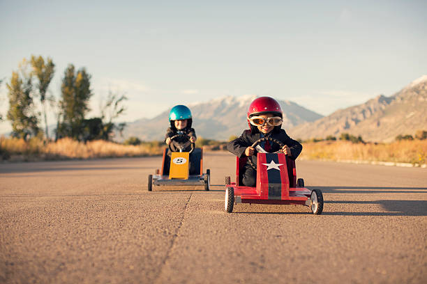 joven negocio muchachos en trajes de carreras de coches de juguete - car child teamwork sports race fotografías e imágenes de stock