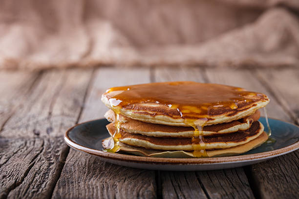 Pancake folded stack of with liquid honey Pancake folded stack of with liquid honey on wooden background.selective focus. PANCAKE Syrup stock pictures, royalty-free photos & images
