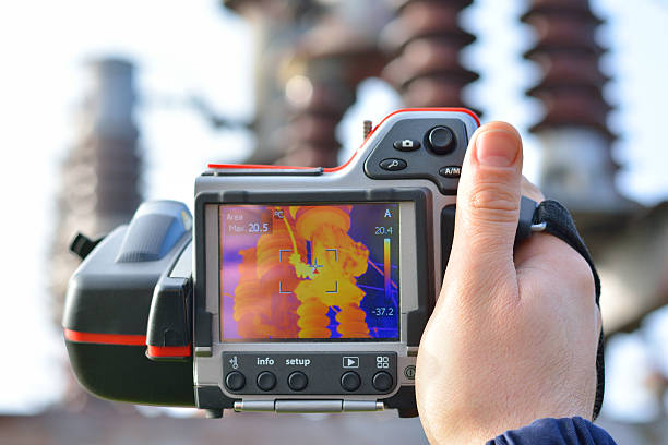 Thermal Imaging and Camera Engineer works with thermal infrared camera. Electrician is in thermographic inspection in power substation, he checks temperature and heating of transformer in power substation. thermal image stock pictures, royalty-free photos & images