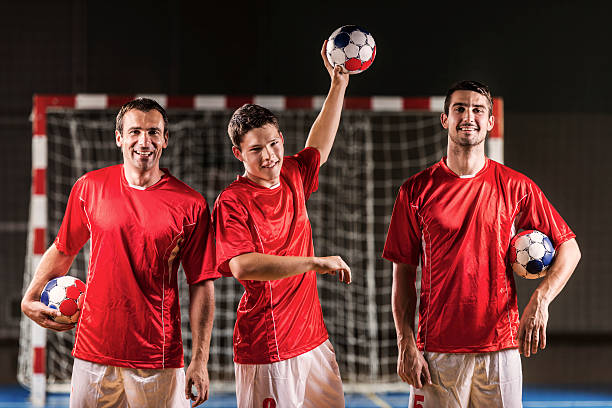 Three handball players. Happy handball players holding balls and looking at the camera.   team handball stock pictures, royalty-free photos & images