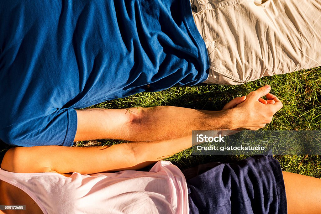 Feeling happy together. Top view of loving couple holding hands while lying on the green grass Grass Stock Photo
