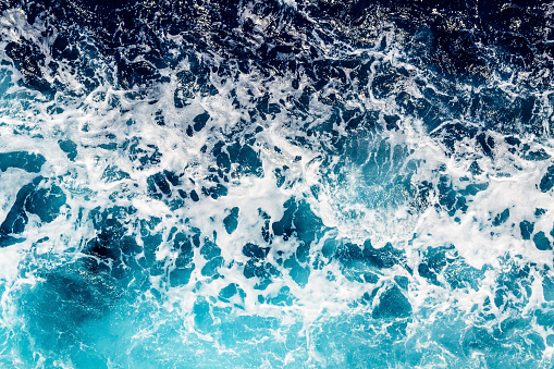 Areal shot of deep blue and rough sea with lot of sea spray