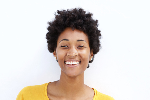 Closeup portrait of smiling young black woman against white background